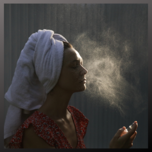 Woman keeping her skin hydrated during skin detox by spraying water on face